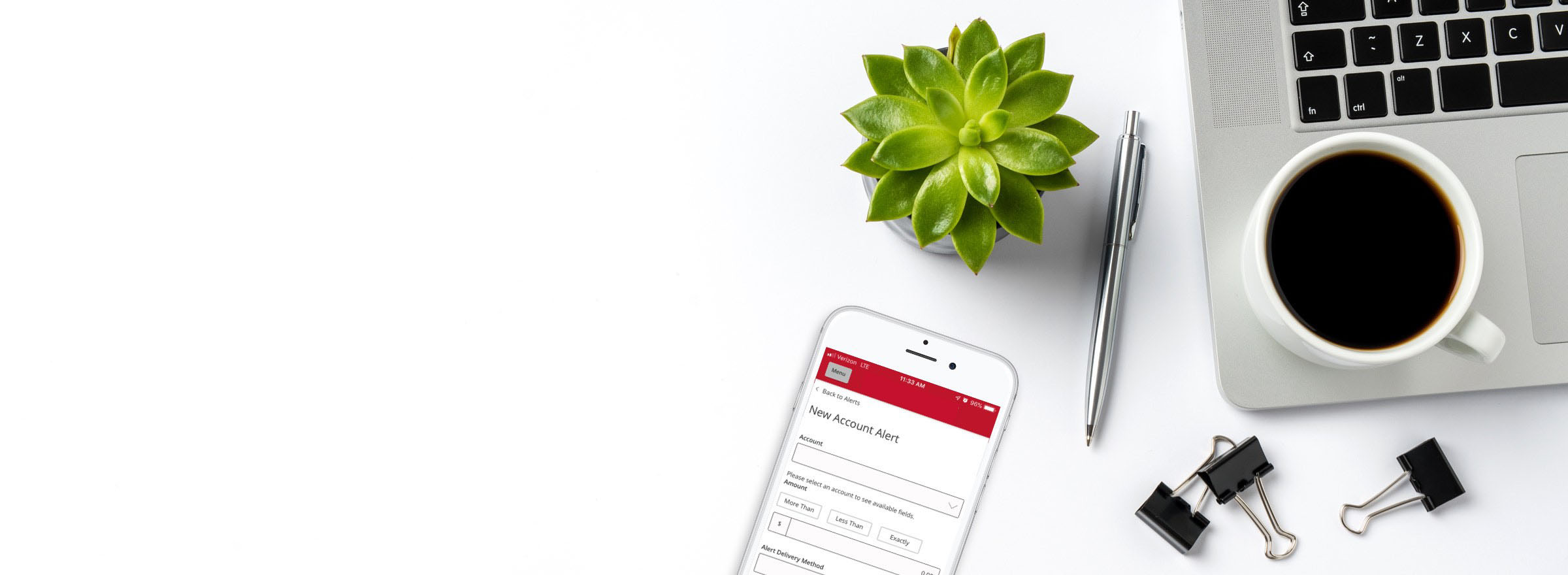 Phone with Southgate Credit Union app alerts screen, laptop on tabletop